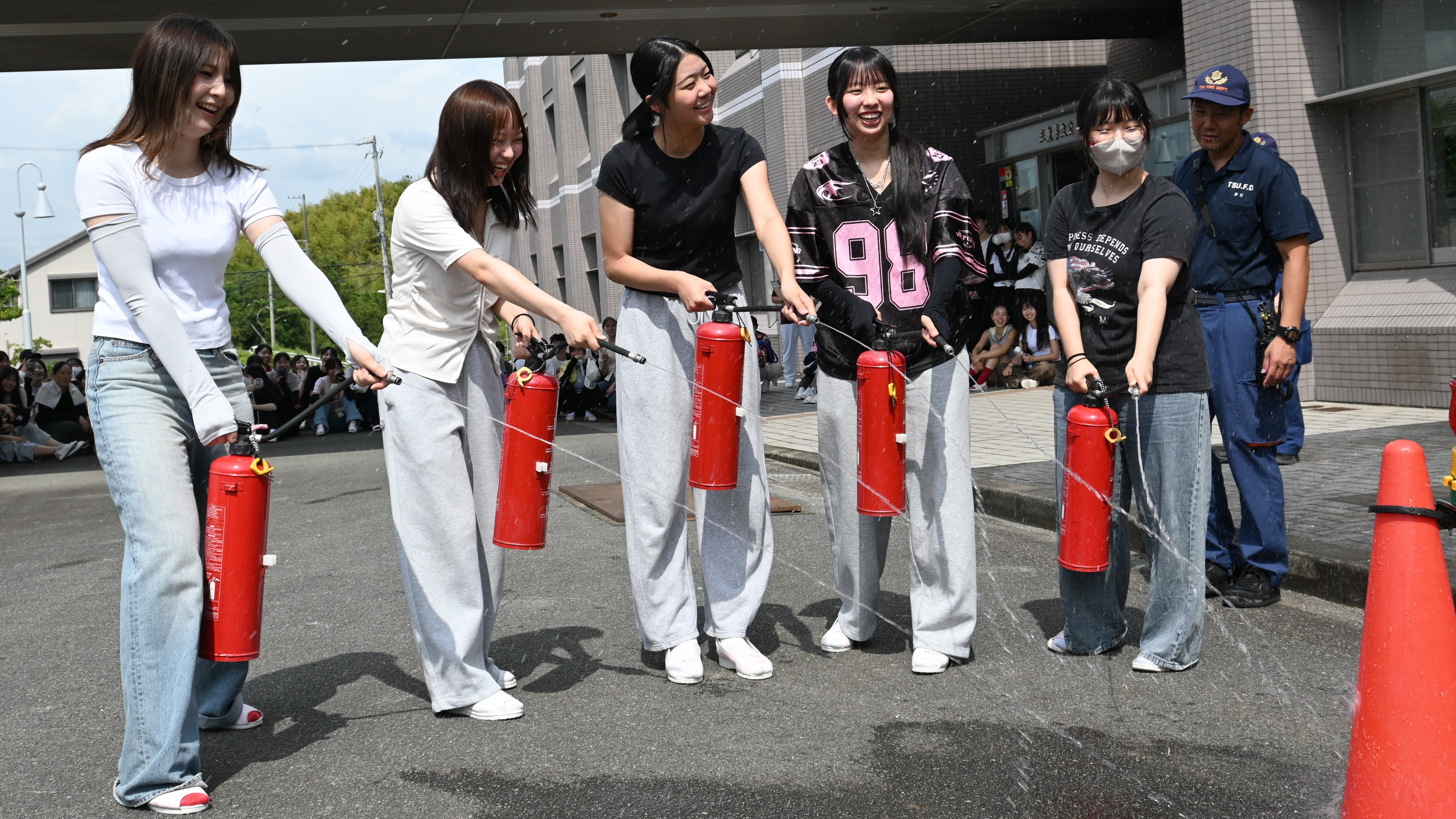 水消火器を使用して初期消火訓練に取り組む学生